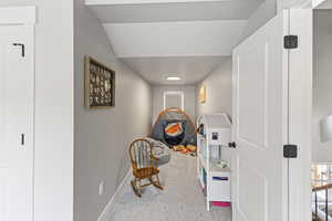 Corridor with carpet flooring, baseboards, and vaulted ceiling