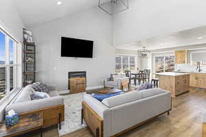 Living area with light wood-style floors, high vaulted ceiling, recessed lighting, and a chandelier