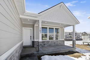 View of exterior entry with covered porch and stone siding