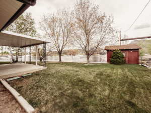 View of yard featuring a patio, fence, and an outbuilding