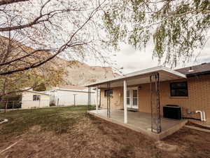 Rear view of property with fence, a patio, brick siding, central AC unit, and a mountain view