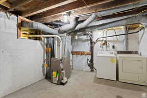 Unfinished below grade area featuring heating unit and independent washer and dryer