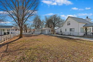 View of side of home with a residential view, an outbuilding, and fence