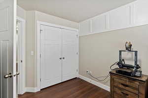 Unfurnished bedroom with dark wood-type flooring, a closet, and baseboards