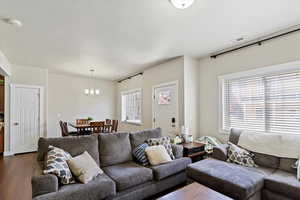 Living room with a chandelier, visible vents, and dark wood-style floors