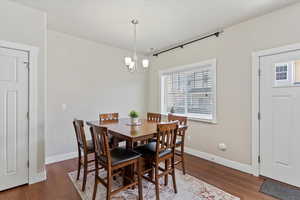 Dining room with wood finished floors, a chandelier, and baseboards