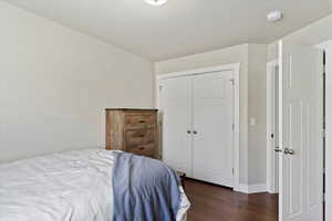 Bedroom featuring dark wood-style flooring, a closet, and baseboards