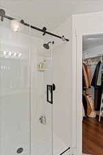 Full bathroom with wood finished floors, a stall shower, and a walk in closet