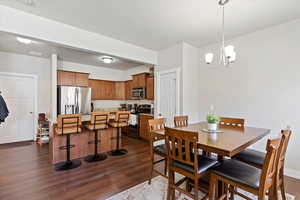 Dining area with an inviting chandelier, visible vents, and dark wood finished floors