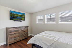 Bedroom with dark wood-type flooring and baseboards