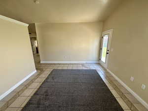 Unfurnished room featuring baseboards and light tile patterned floors with a custom rug.