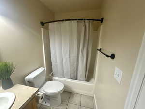 Bathroom featuring toilet, tile patterned floors, shower / bath combination with curtain, and vanity