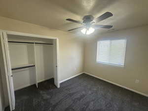 Unfurnished bedroom featuring visible vents, a closet, baseboards, dark colored carpet, and a textured ceiling