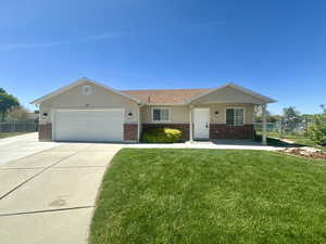 Single story home featuring brick siding, an attached garage, fence, and a front yard