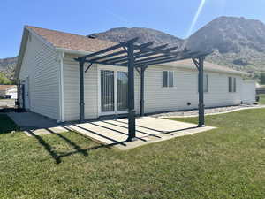 Rear view of house featuring a lawn, a pergola, a mountain view, and roof with shingles