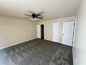 Unfurnished bedroom with baseboards, ceiling fan, and dark colored carpet