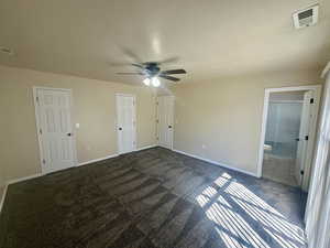 Unfurnished bedroom featuring visible vents, baseboards, and dark carpet