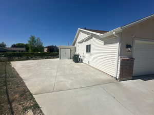 View of property exterior with a patio area and a storage unit