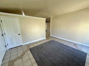 Spare room featuring baseboards, ceiling fan, ornamental molding, and light tile patterned floors