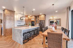 Kitchen with dobule oven black, a chandelier, recessed lighting, a kitchen island, and stainless steel refrigerator with ice dispenser
