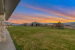 Yard at dusk with a playground and fence
