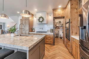 Kitchen featuring a breakfast bar area, brown cabinets, a sink, stainless steel appliances, and recessed lighting