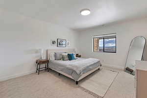 Bedroom with baseboards, visible vents, and light colored carpet