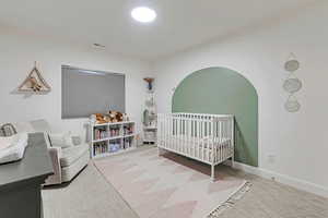 Basement bedroom with visible vents, baseboards, and a nursery area