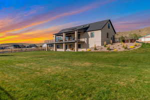 Back of house at dusk featuring a lawn, a wooden deck, stucco siding, and a fenced backyard