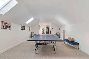 Loft room with carpet flooring, baseboards, and lofted ceiling with skylight