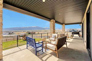 View of covered terrace featuring a mountain view, an outdoor hangout area, and fence