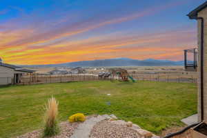 Yard at dusk featuring a fenced backyard, a playground, and a mountain view