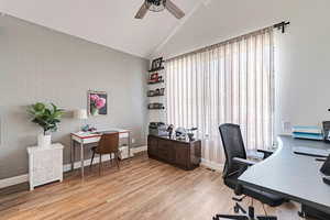 Office area featuring ceiling fan, brick wall, baseboards, light wood-type flooring, and visible vents