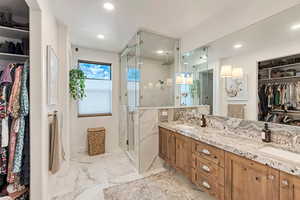 Primary full bath featuring a sink, a shower stall, double vanity, and marble finish floor