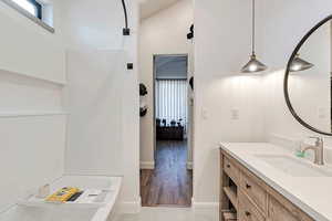 Bathroom with vanity, baseboards, ensuite bathroom, and wood finished floors