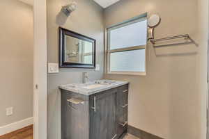 Bathroom featuring baseboards, vanity, and wood finished floors