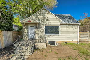 View of front of house featuring fence and a shingled roof