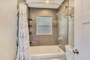 Bathroom with toilet and shower / bath combination with curtain