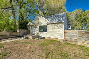 Exterior space with a fenced backyard, roof with shingles, and a front yard