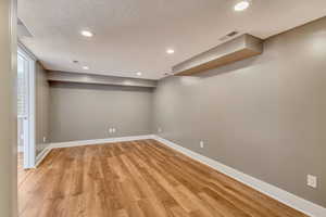 Below grade area with visible vents, recessed lighting, light wood-style floors, and baseboards