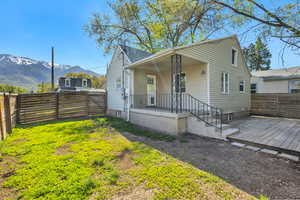 Bungalow with a fenced backyard, covered porch, a deck with mountain view, and roof with shingles