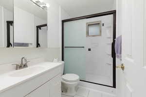 Full bathroom with vanity, toilet, tile patterned flooring, and a stall shower