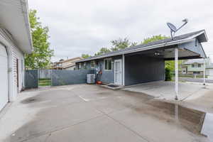 View of home's exterior featuring fence, driveway, a patio area, and a carport