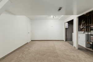 Finished basement with visible vents, washer and clothes dryer, carpet, and baseboards
