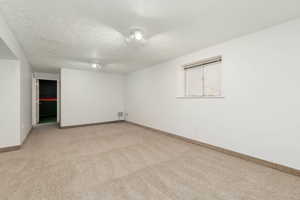 Unfurnished room featuring light colored carpet, a textured ceiling, and baseboards