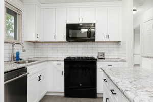 Kitchen with a sink, decorative backsplash, white cabinets, and black appliances