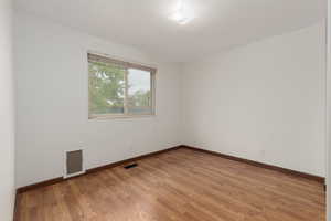 Empty room featuring baseboards, visible vents, and light wood-style floors