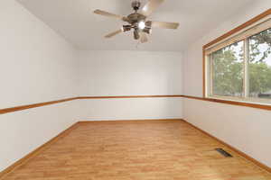 Spare room with a ceiling fan, baseboards, visible vents, and light wood finished floors
