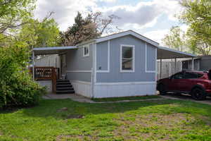 View of front of house featuring a deck, a front yard, and an attached carport