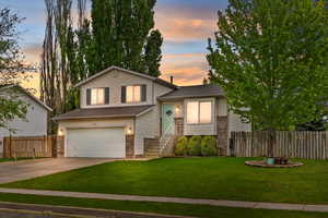 Tri-level home featuring fence, an attached garage, concrete driveway, and a front yard